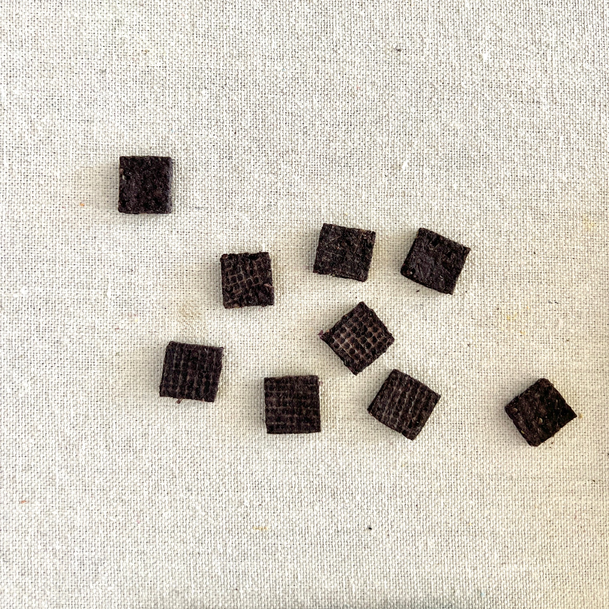 Small dark brown square tiles on a light fabric background