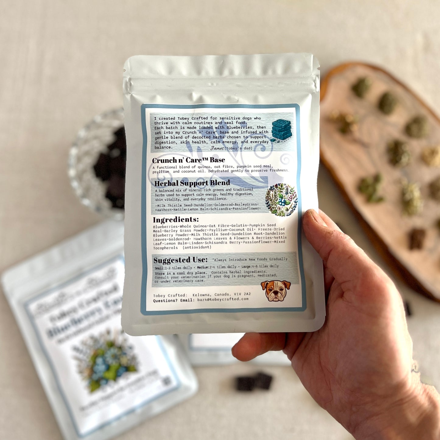 Hand holding a package of Crunch & Care with ingredients list on a neutral background