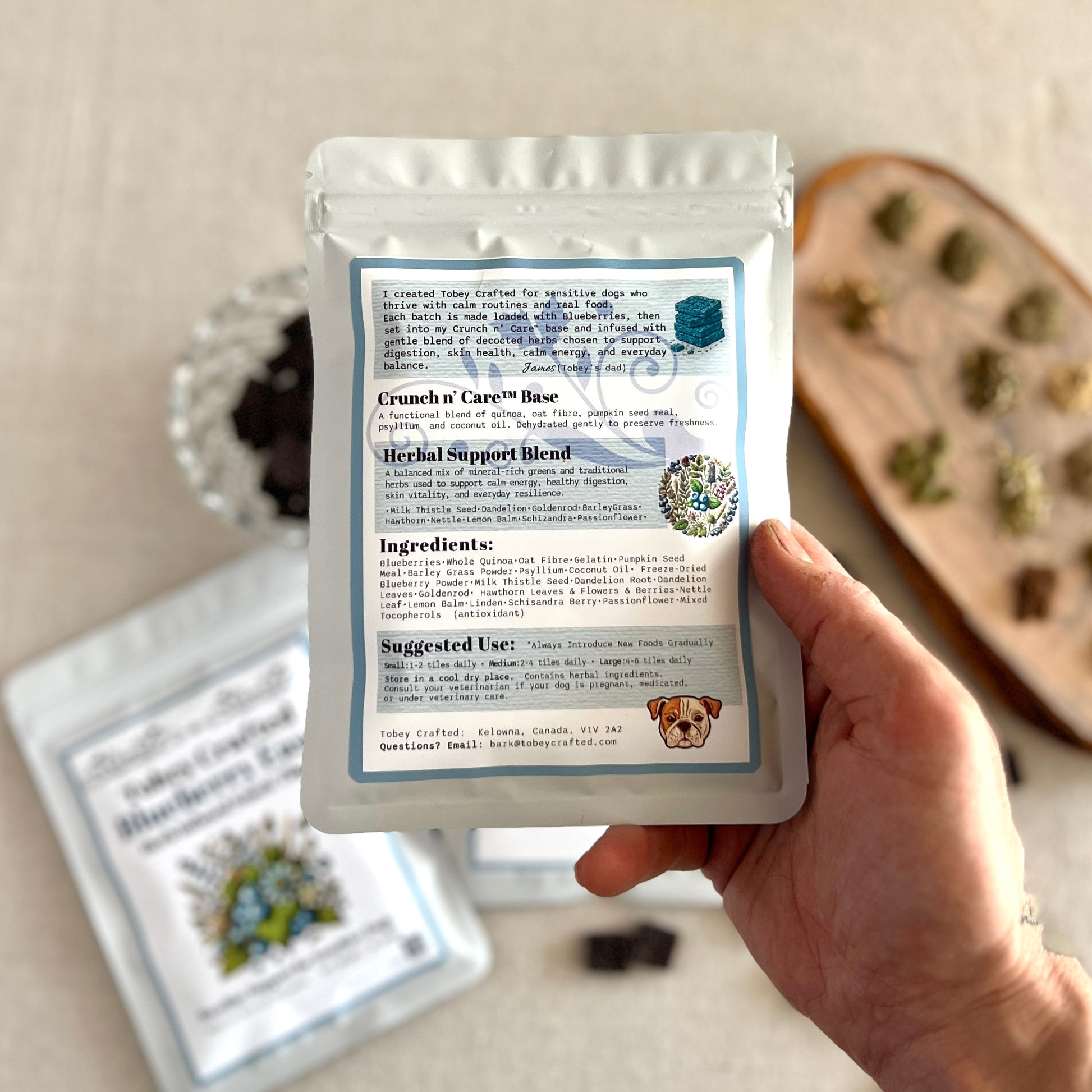 Hand holding a package of Crunch & Care with ingredients list on a neutral background