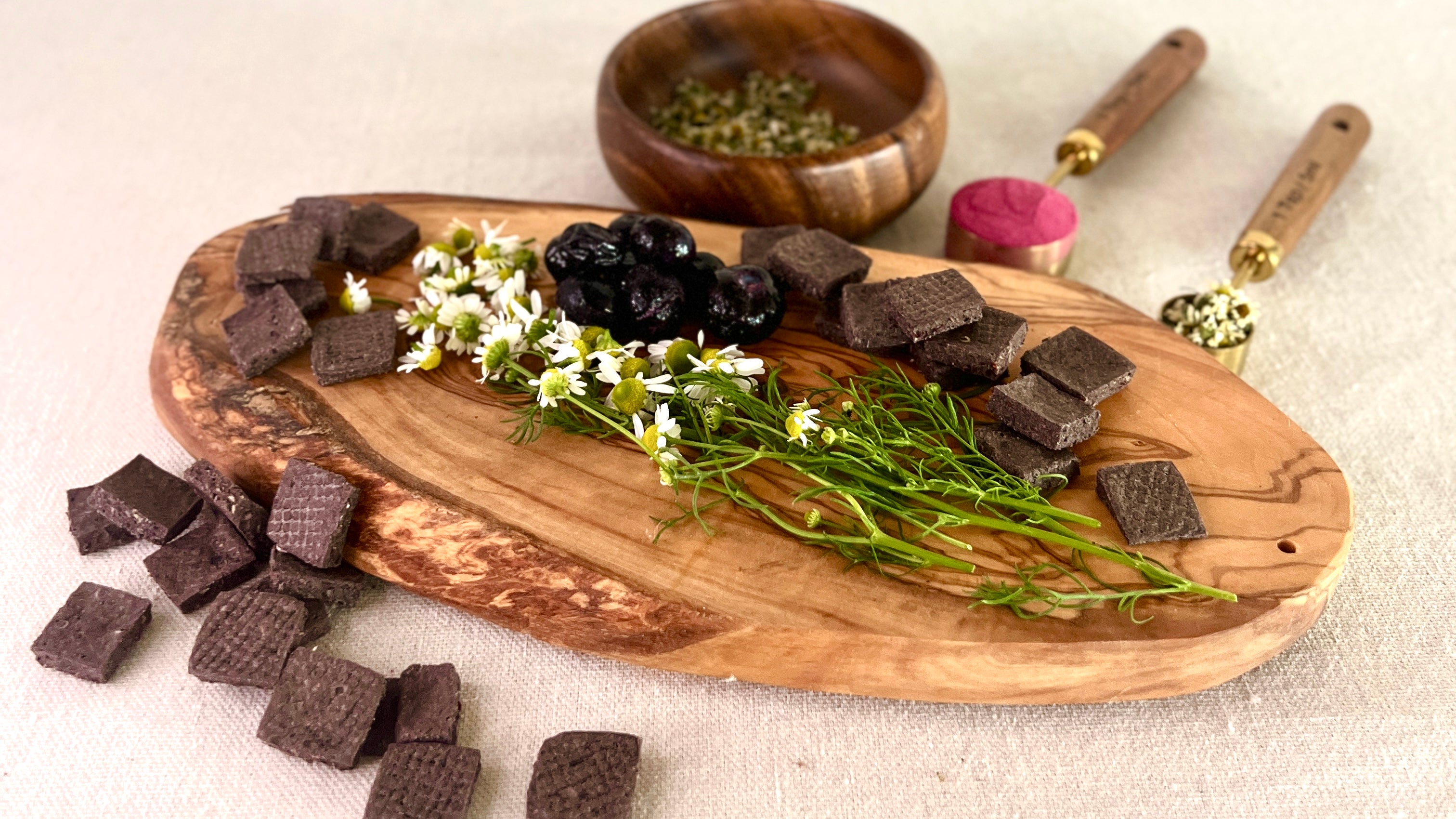 Fresh chamomile and blueberries are arranged on a wooden cutting board
