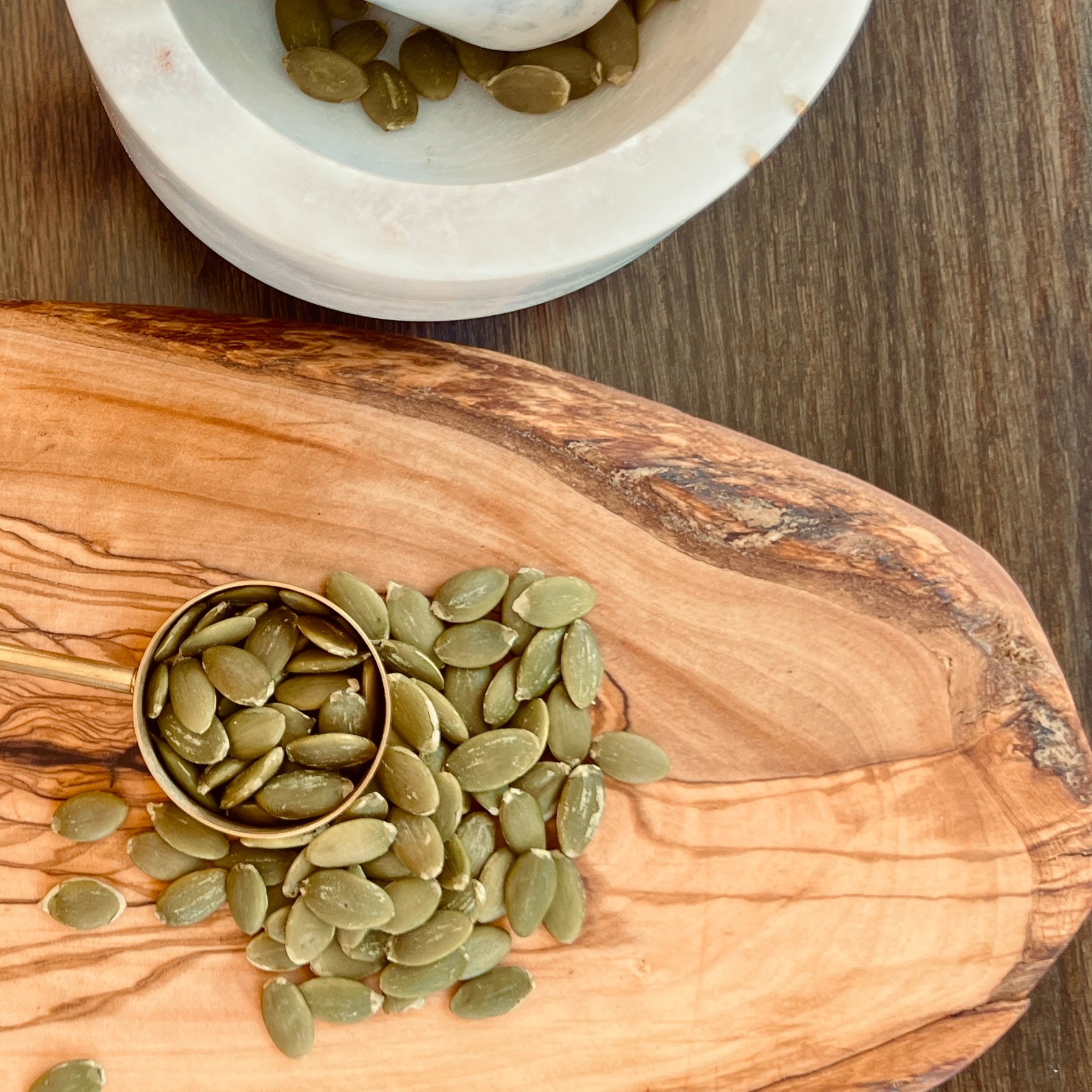 a top view of pumpkin seeds on a wooden cutting board