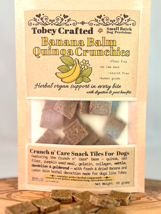 Packaging of Tobey Crafted Banana Balm Quinoa Crunchies dog treats with text and images on a wooden surface.