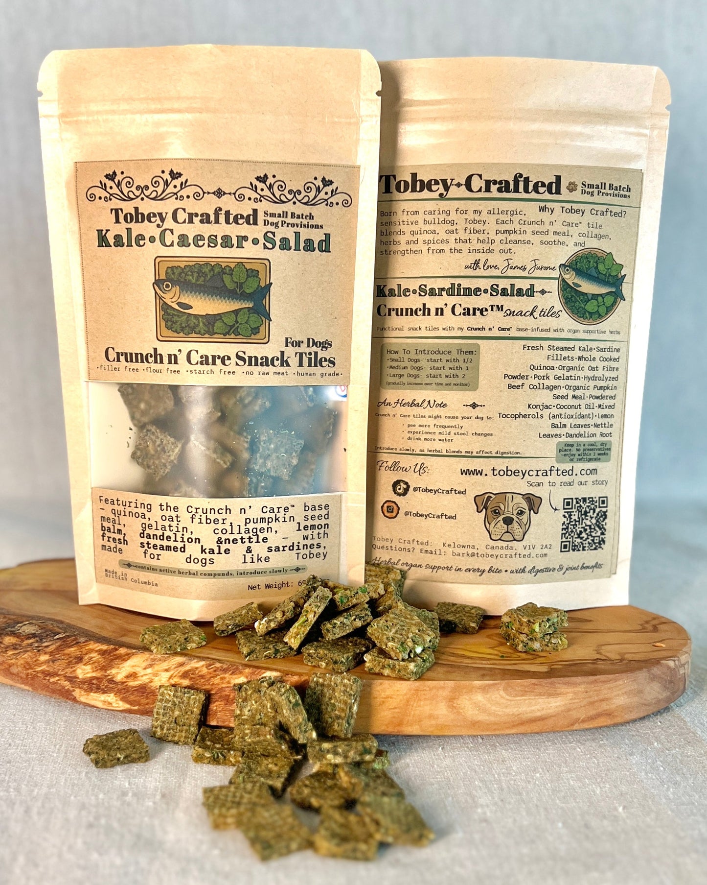 Two packages of Tobey-Crafted Kale Caesar Salad with snack tiles on a wooden board.