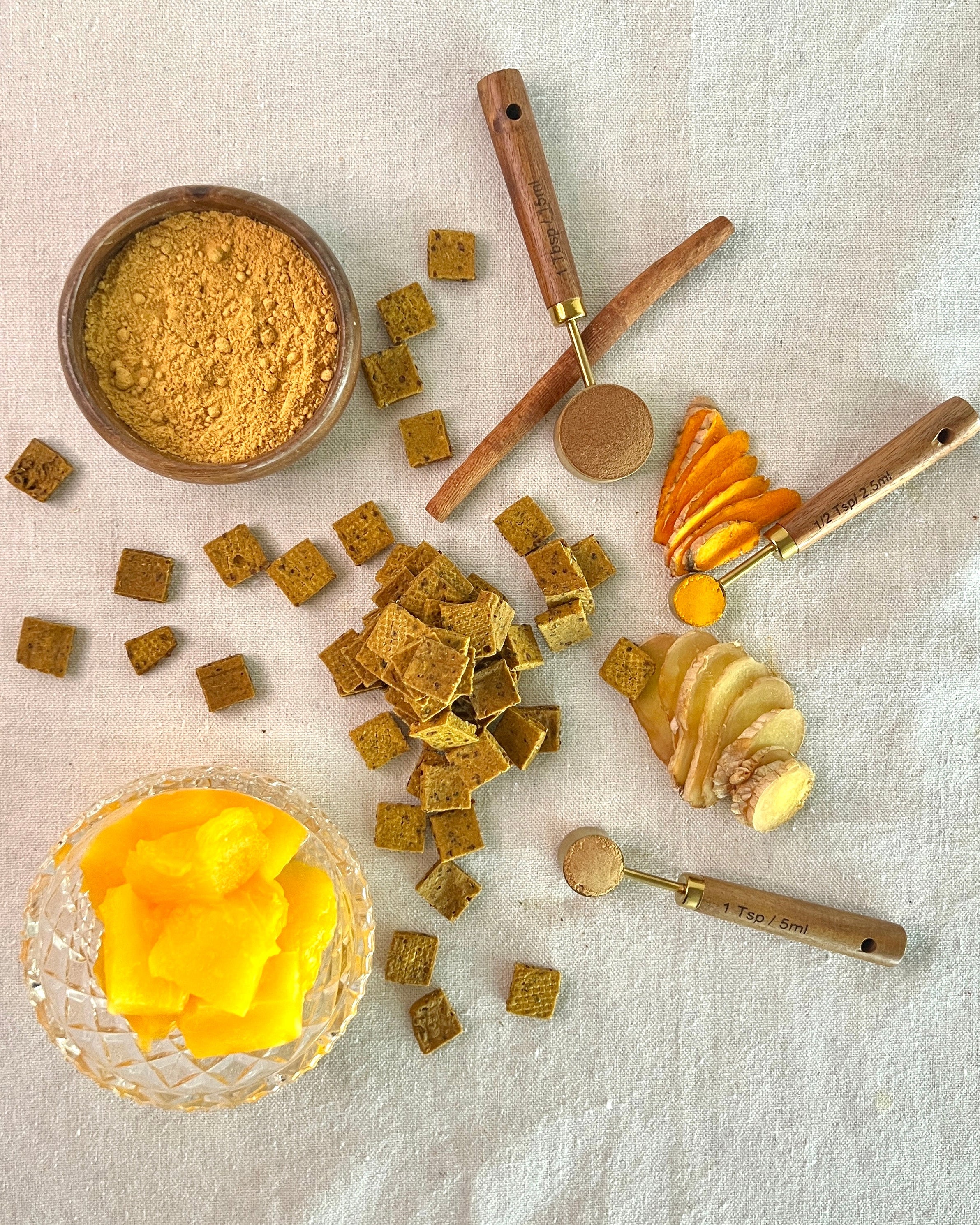Spices and seasonings including ground ginger, pumpkin cubes, and a jar of cinnamon powder on a textured surface.
