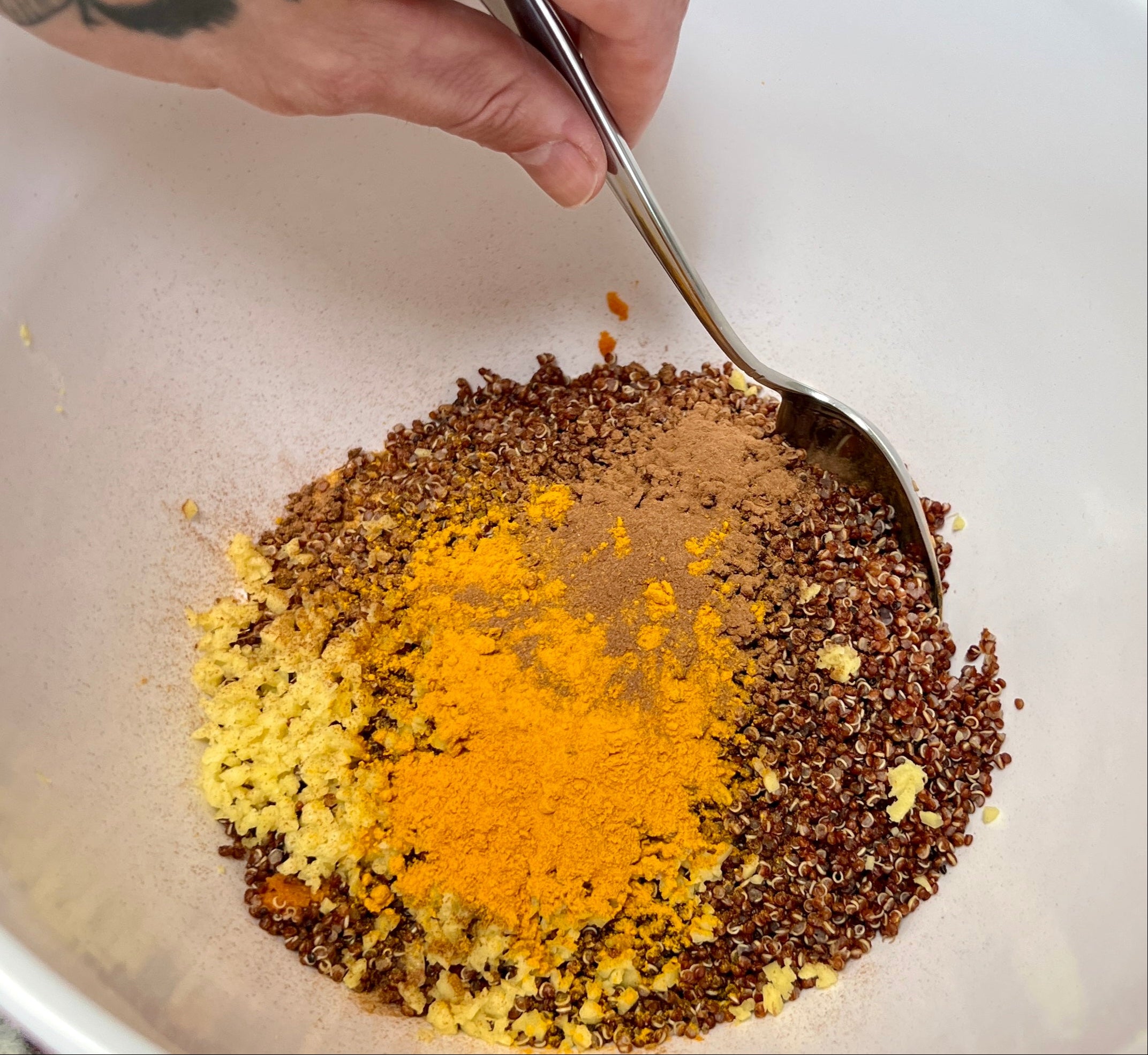 Hand with a spoon adding spices to a bowl
